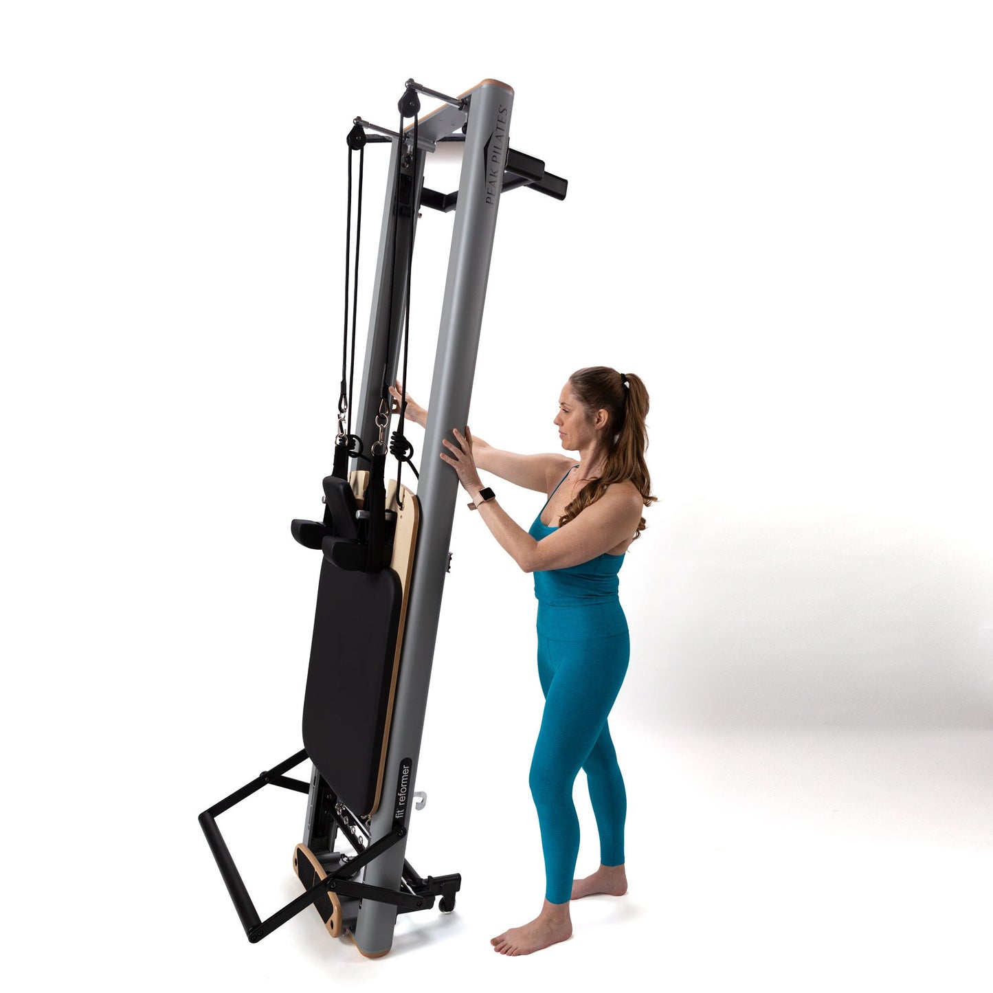 Woman adjusting a Pilates reformer machine on a white background